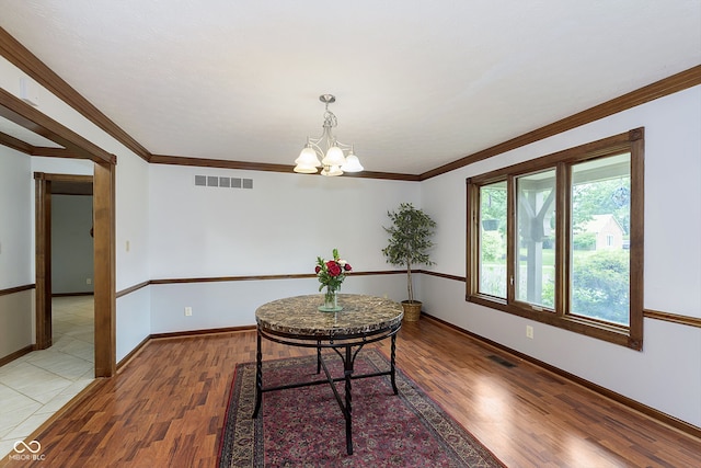 dining area featuring hardwood / wood-style flooring, crown molding, and a chandelier