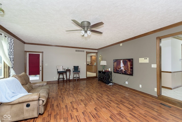 living room featuring hardwood / wood-style floors, ceiling fan, ornamental molding, and a textured ceiling