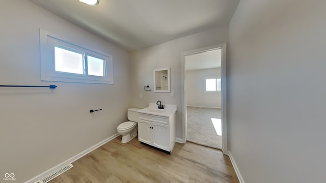 bathroom with toilet, hardwood / wood-style floors, and vanity