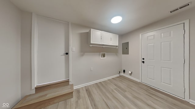 clothes washing area featuring light hardwood / wood-style flooring, washer hookup, electric panel, and cabinets