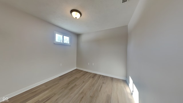 unfurnished room featuring a textured ceiling and light wood-type flooring