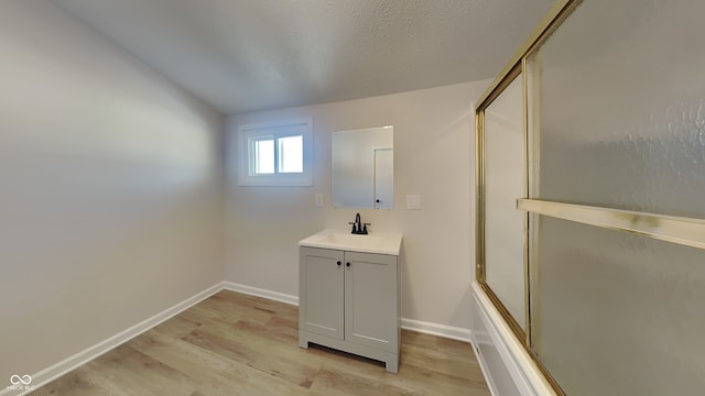 bathroom featuring hardwood / wood-style floors, vanity, and shower / bath combination with glass door