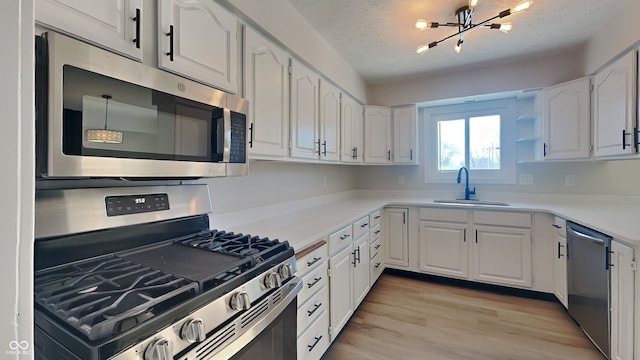 kitchen with white cabinets, a chandelier, sink, and stainless steel appliances