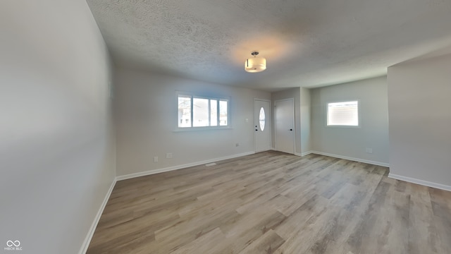 unfurnished room with plenty of natural light, a textured ceiling, and light hardwood / wood-style flooring