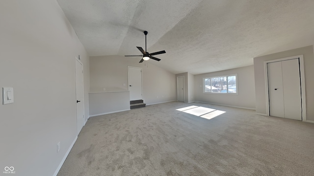 unfurnished living room featuring ceiling fan, light colored carpet, a textured ceiling, and lofted ceiling