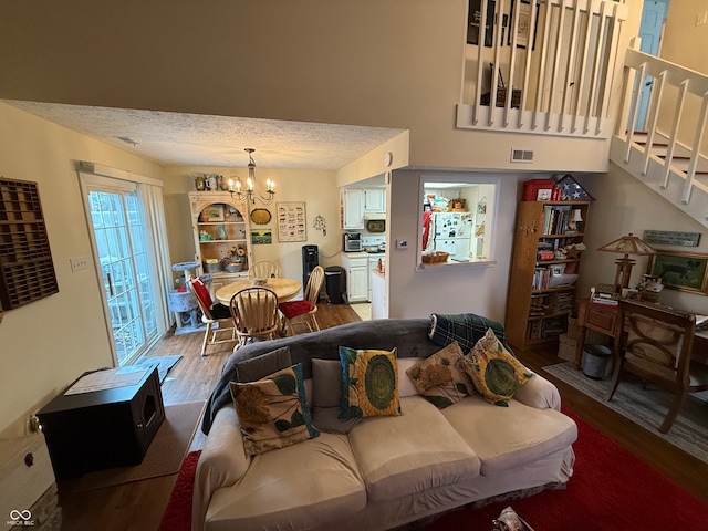 living room featuring wood-type flooring, a textured ceiling, and a notable chandelier