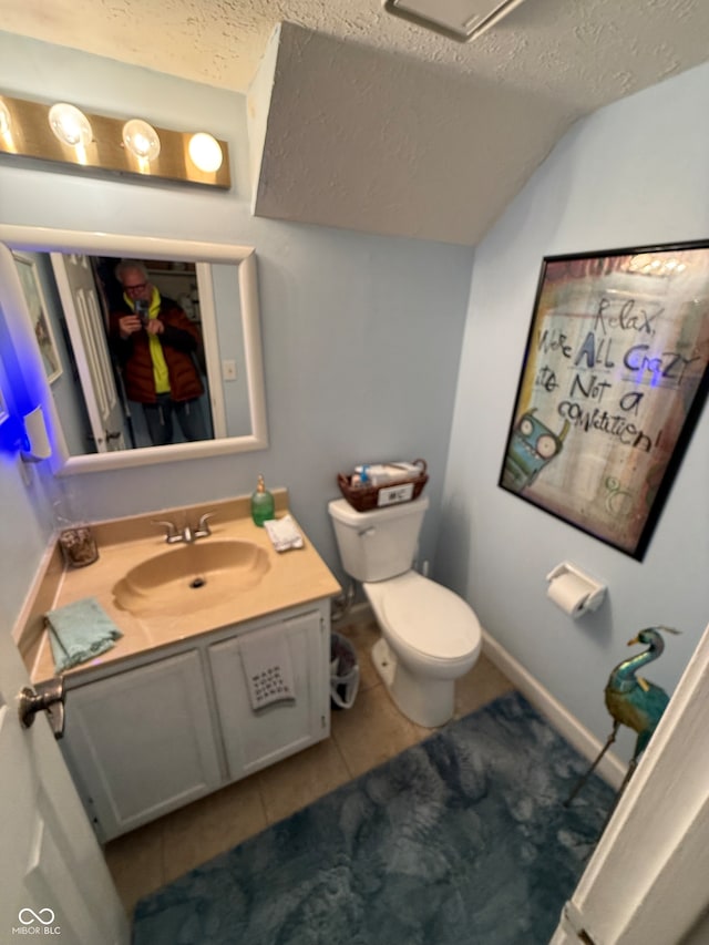 bathroom featuring vanity, lofted ceiling, tile patterned flooring, toilet, and a textured ceiling