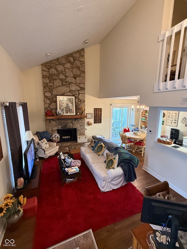 living room with a stone fireplace, hardwood / wood-style floors, high vaulted ceiling, and a chandelier