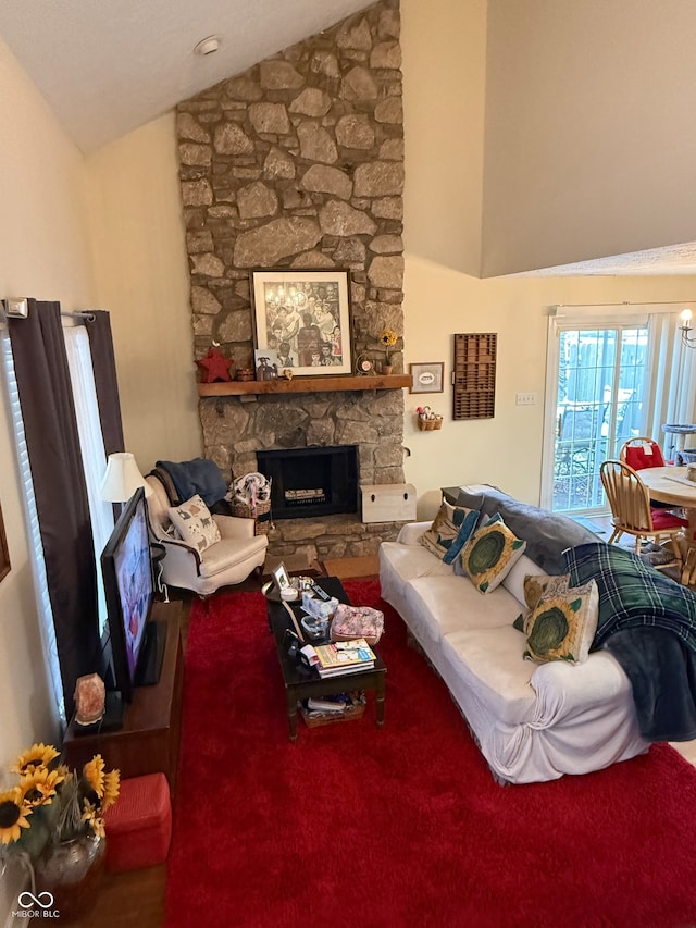 living room with a stone fireplace and high vaulted ceiling