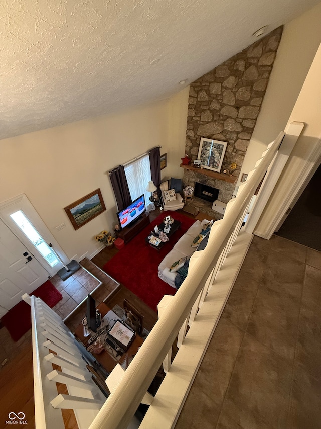 living room featuring a stone fireplace, lofted ceiling, and a textured ceiling