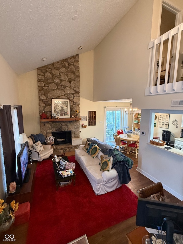 living room featuring hardwood / wood-style floors, high vaulted ceiling, an inviting chandelier, a fireplace, and a textured ceiling