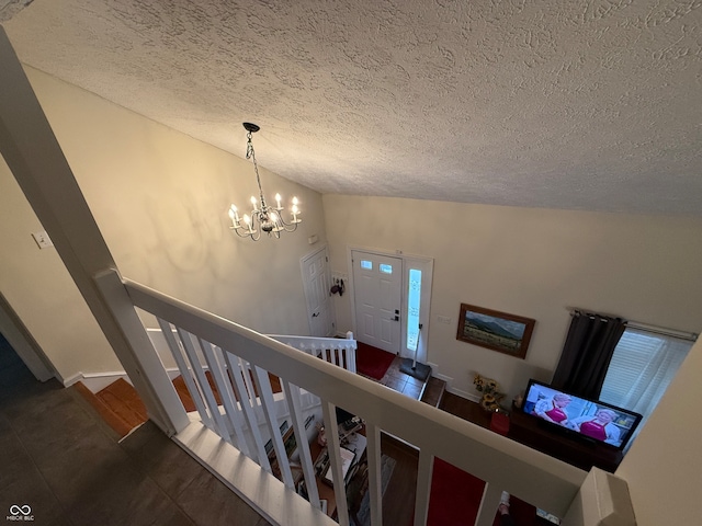 stairway featuring tile patterned floors, a notable chandelier, a textured ceiling, and high vaulted ceiling