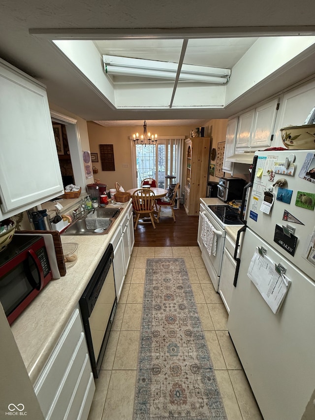 kitchen with sink, light tile patterned floors, a notable chandelier, white cabinets, and black appliances