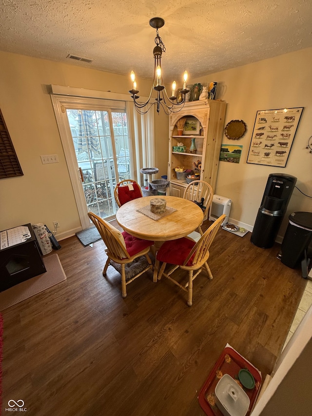 dining room featuring a textured ceiling, an inviting chandelier, and dark wood-type flooring