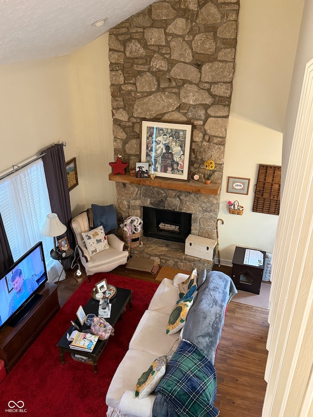 living room with a textured ceiling, a fireplace, dark wood-type flooring, and vaulted ceiling