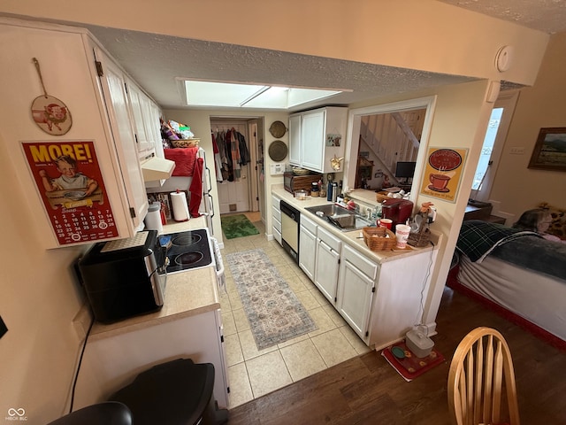 kitchen featuring ventilation hood, sink, stainless steel dishwasher, light hardwood / wood-style floors, and white cabinetry