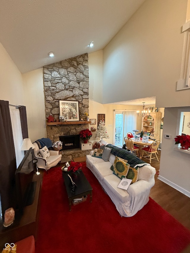 living room with high vaulted ceiling, hardwood / wood-style flooring, a stone fireplace, and an inviting chandelier