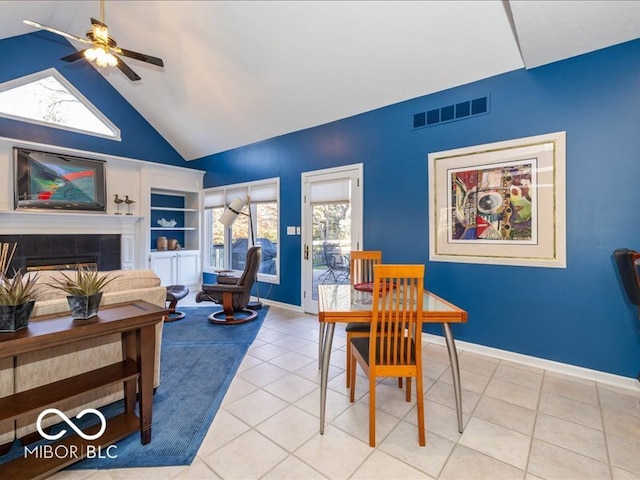 dining area with light tile patterned floors, ceiling fan, a healthy amount of sunlight, and a tiled fireplace