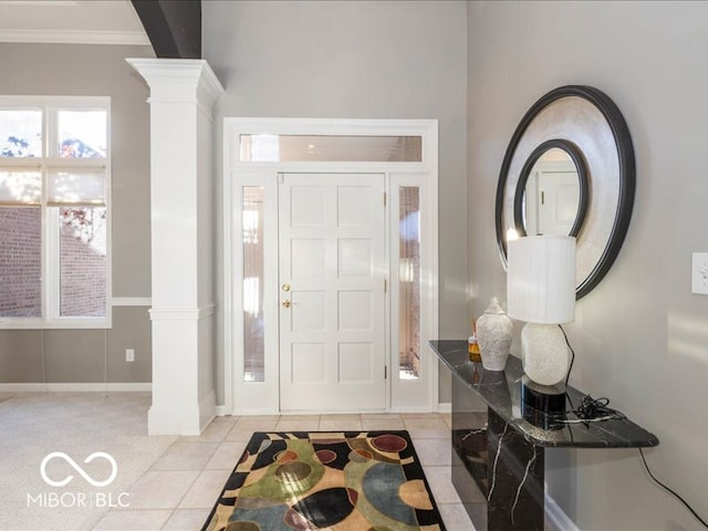 entrance foyer with light tile patterned floors, ornate columns, and crown molding