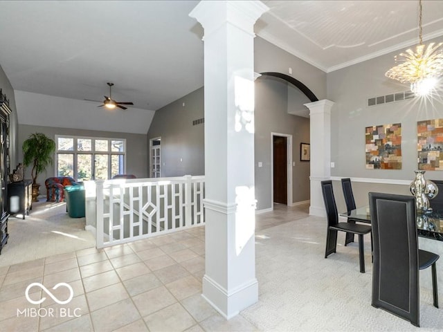 dining space with ceiling fan with notable chandelier, crown molding, vaulted ceiling, light colored carpet, and decorative columns