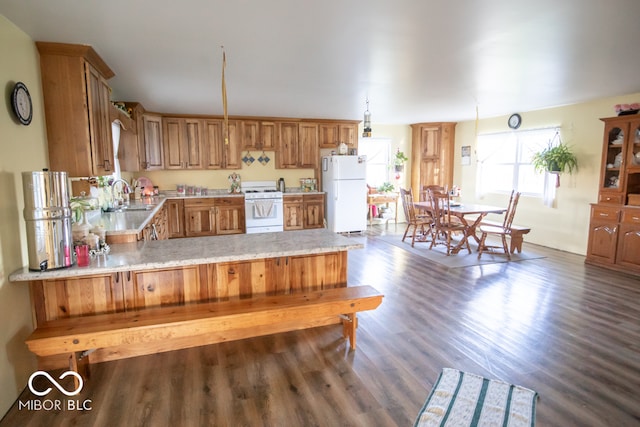 kitchen with kitchen peninsula, dark hardwood / wood-style flooring, white appliances, and sink