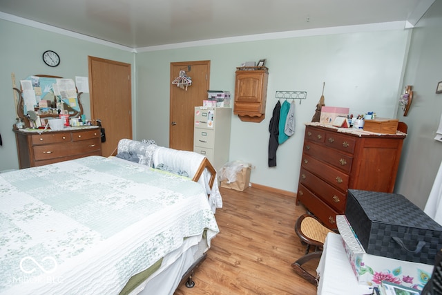 bedroom featuring a closet, light hardwood / wood-style flooring, and ornamental molding