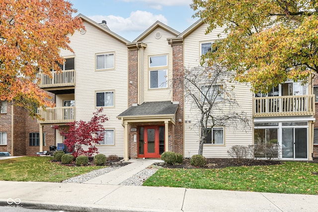 multi unit property with a front yard and a balcony