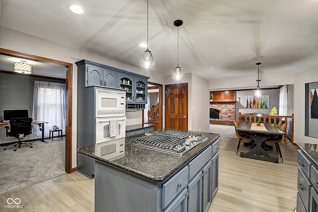 kitchen featuring a fireplace, pendant lighting, white appliances, and light hardwood / wood-style flooring