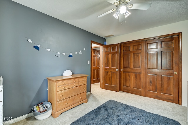 bedroom with ceiling fan, light carpet, and a textured ceiling