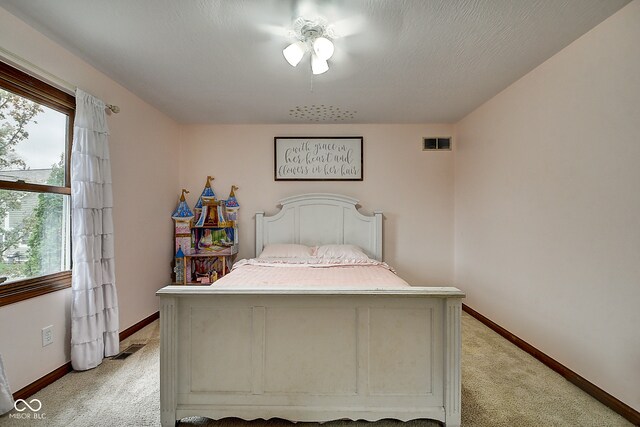 bedroom with ceiling fan, light carpet, and a textured ceiling