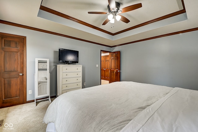 carpeted bedroom with a tray ceiling, ceiling fan, and ornamental molding