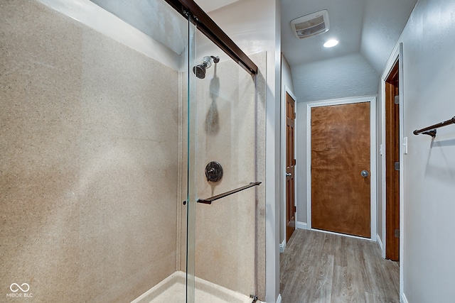 bathroom featuring wood-type flooring, an enclosed shower, and lofted ceiling