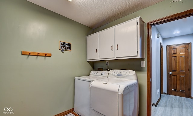 washroom featuring cabinets, a textured ceiling, separate washer and dryer, and light hardwood / wood-style flooring