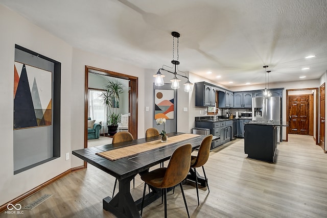 dining space with a notable chandelier, light wood-type flooring, and sink