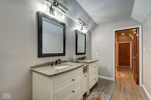 bathroom featuring wood-type flooring, vanity, and lofted ceiling