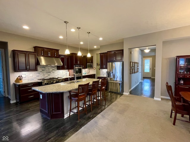 kitchen with a kitchen breakfast bar, pendant lighting, sink, an island with sink, and stainless steel appliances