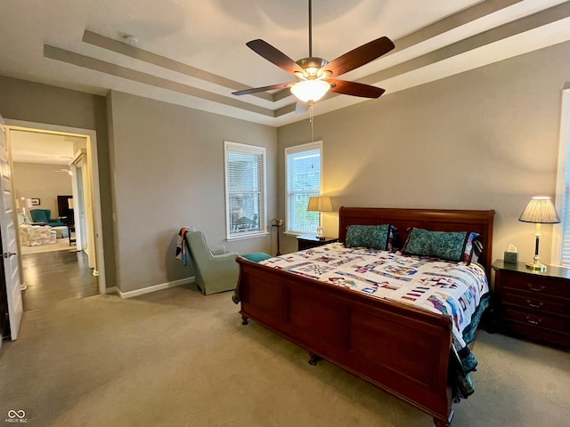 bedroom with ceiling fan, carpet floors, and a tray ceiling