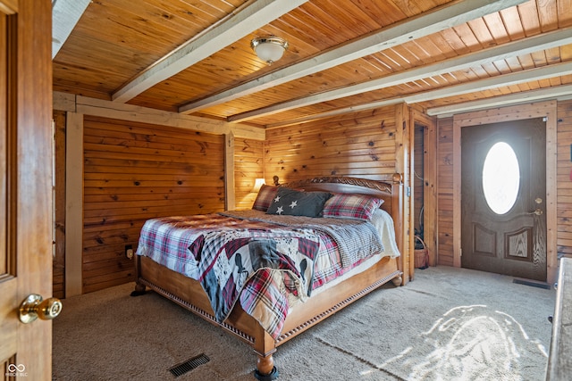 carpeted bedroom with beam ceiling, wooden walls, and wood ceiling