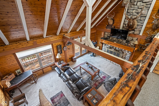 living area with wooden walls, high vaulted ceiling, beam ceiling, wooden ceiling, and carpet flooring