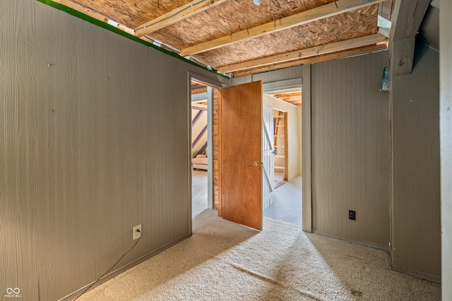 carpeted spare room with wooden walls