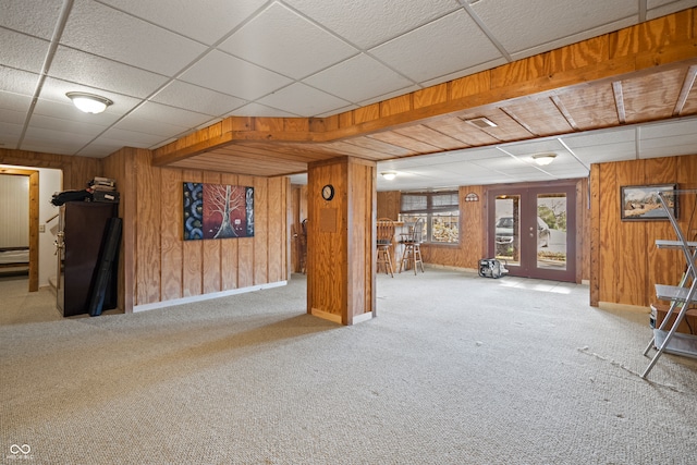 below grade area featuring carpet flooring, french doors, baseboards, and wood walls