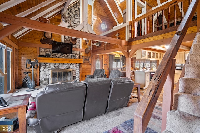 carpeted living room featuring stairway, vaulted ceiling with beams, a fireplace, and wood walls