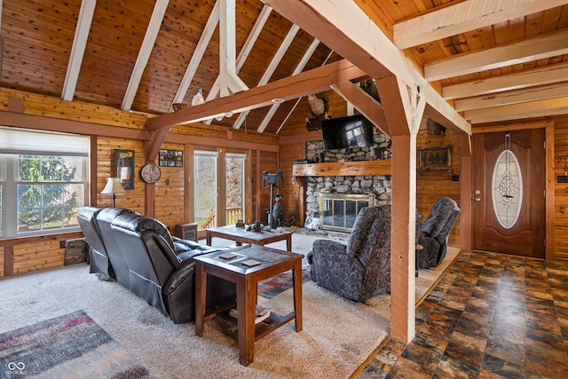 living room with lofted ceiling with beams, wooden walls, a stone fireplace, carpet, and wood ceiling