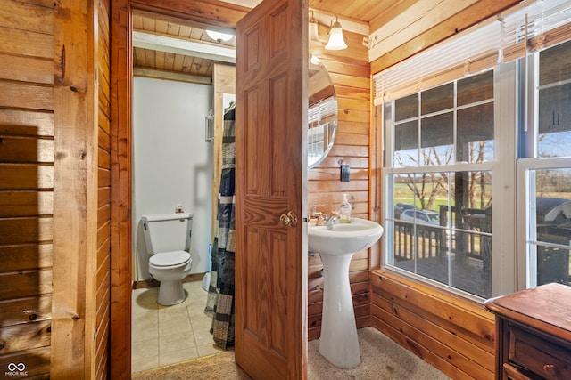 bathroom with beam ceiling, toilet, wood ceiling, and wood walls