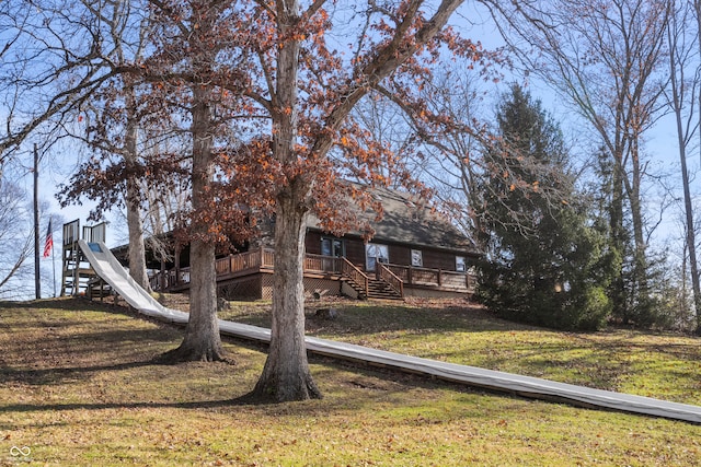 view of front of house with stairway, a wooden deck, and a front lawn