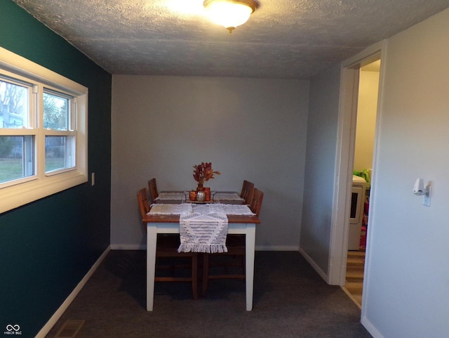 dining area with a textured ceiling and dark colored carpet