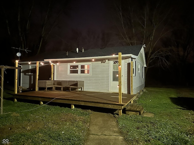 back house at night with a lawn and a wooden deck