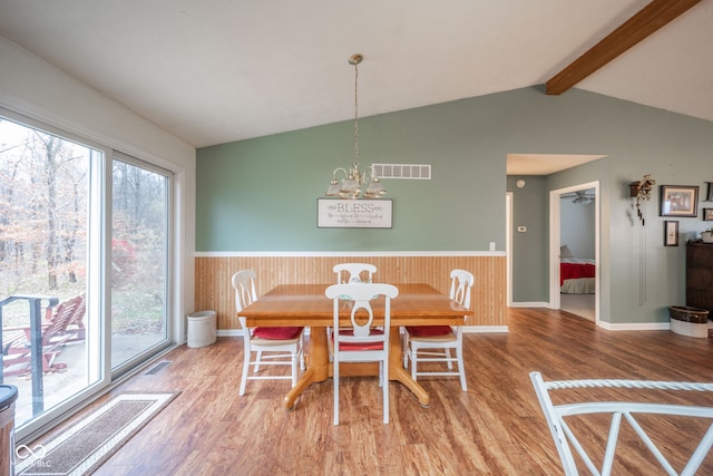 dining space featuring vaulted ceiling with beams, wood walls, hardwood / wood-style floors, and a chandelier