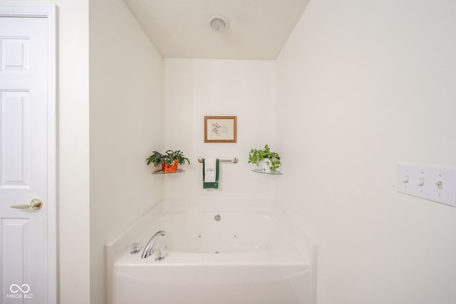 bathroom with a washtub and a textured ceiling