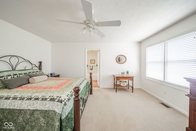 bedroom with light carpet, ensuite bath, and ceiling fan